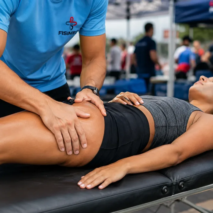 Kinesiólogo de FISIMED realizando descarga muscular en pierna de deportista.