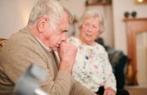 Un adulto mayor tosiendo en su hogar, sugiriendo posibles problemas de salud respiratoria y la importancia de los cuidados y la prevención.