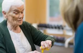 Adulto mayor recibiendo terapia ocupacional en su casa con un terapeuta.