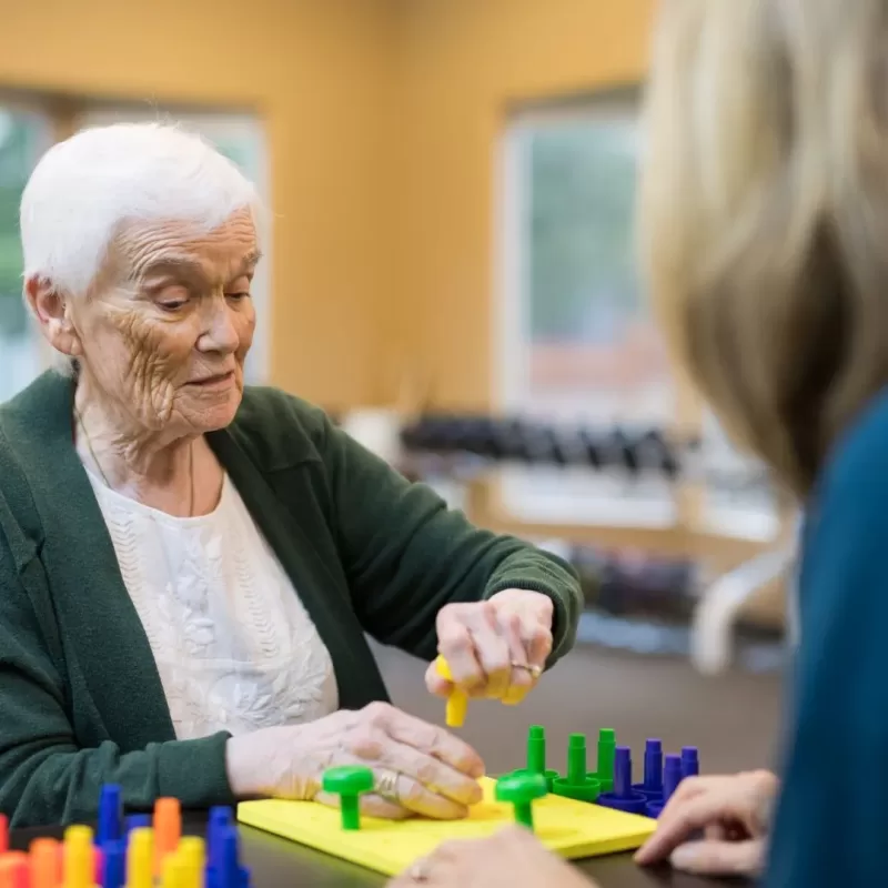 Adulto mayor recibiendo terapia ocupacional en su casa con un terapeuta.